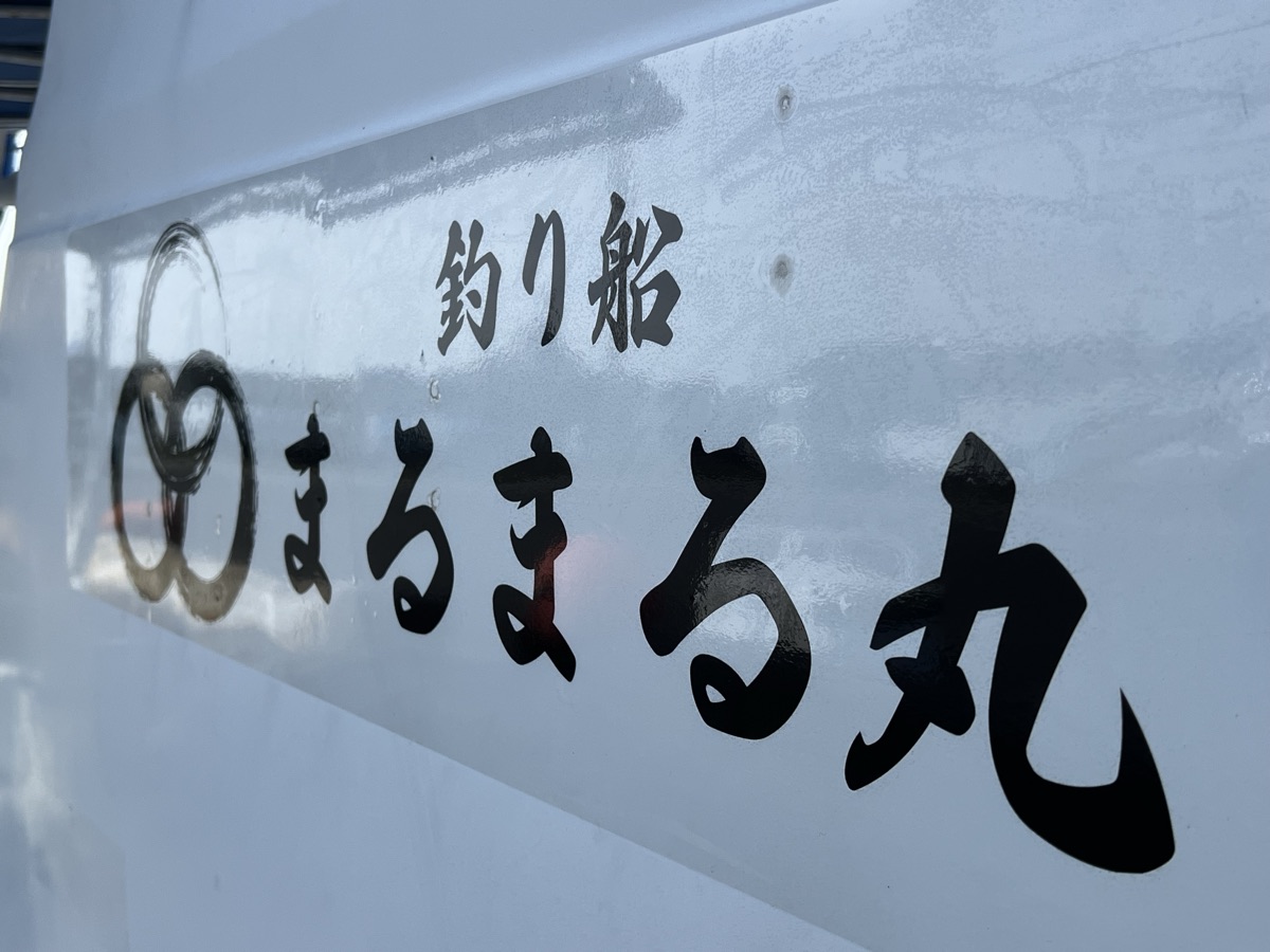 船体に書かれた屋号。三つの輪の印と「釣り船 まるまる丸」の文字
